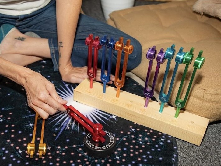 Alicia Wright striking a weighted tuning fork from her chakra set during a sound healing session in Mesa, Arizona