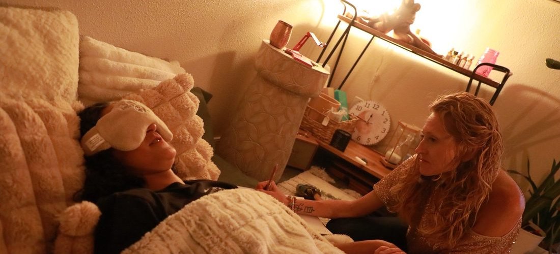 A ketamine-assisted psychotherapy session at The Wild Within in Mesa, Arizona, with a client resting under blankets in an eye mask while a therapist sits alongside
