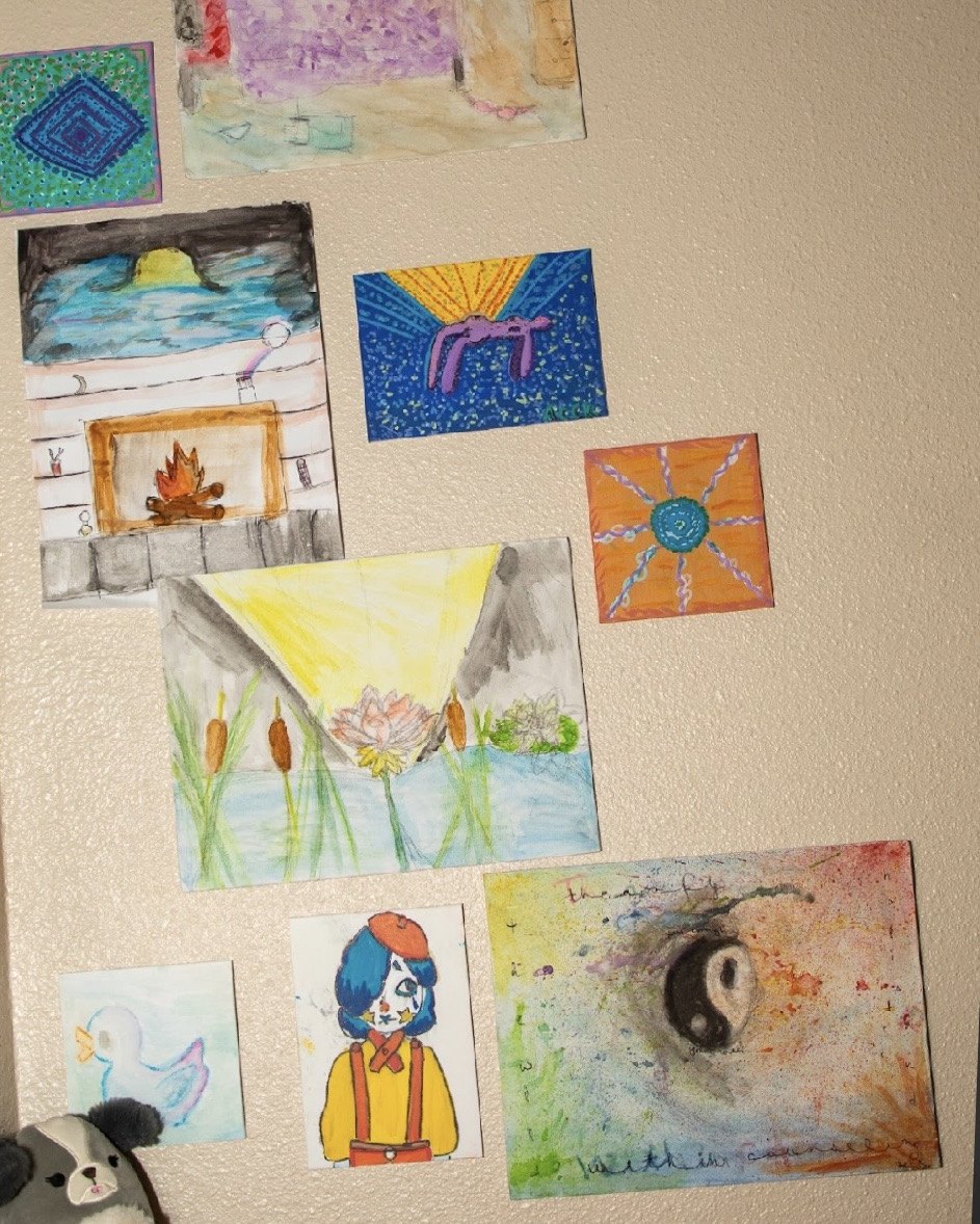 A wall of children's artwork and stuffed animals in Alicia Wright's Mesa, Arizona office, where she does parenting and teen work