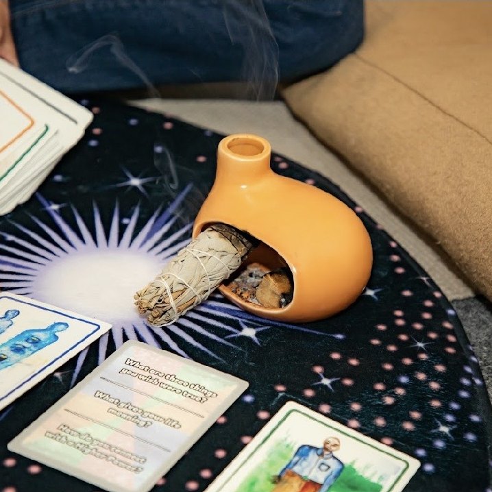 Sage, an oracle card spread and a ceramic vessel laid out for a grounding ritual at The Wild Within in Mesa, Arizona
