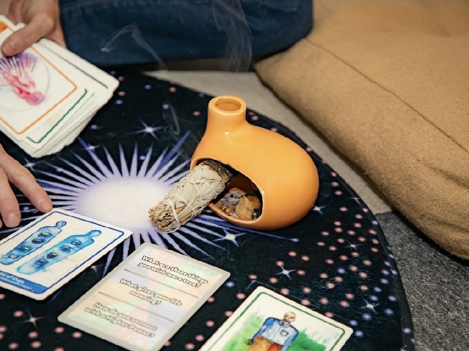 Burning sage, oracle cards and a ceramic vessel set out for energy work at The Wild Within in Mesa, Arizona